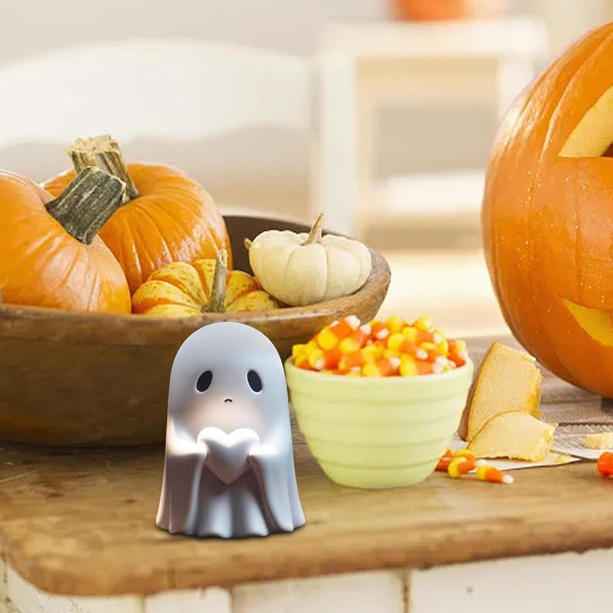 Ghost figurine with heart on a table with pumpkins