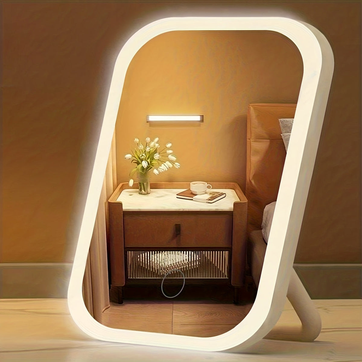 Modern bedroom setup with a large illuminated mirror reflecting a nightstand with a cup and flowers.