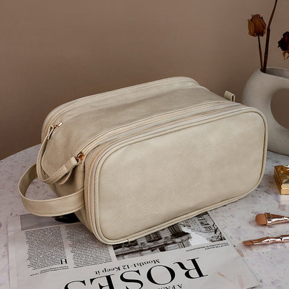 Beige toiletry bag on a surface with a newspaper and decorative items.
