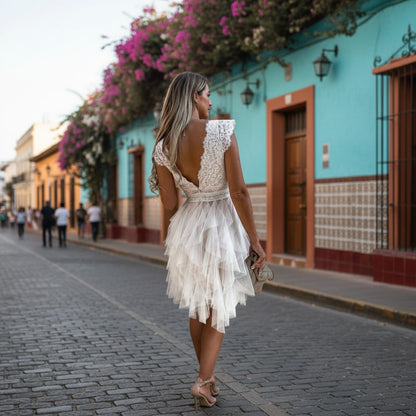 Woman in a white dress walking down a colorful street with flowers and buildings.