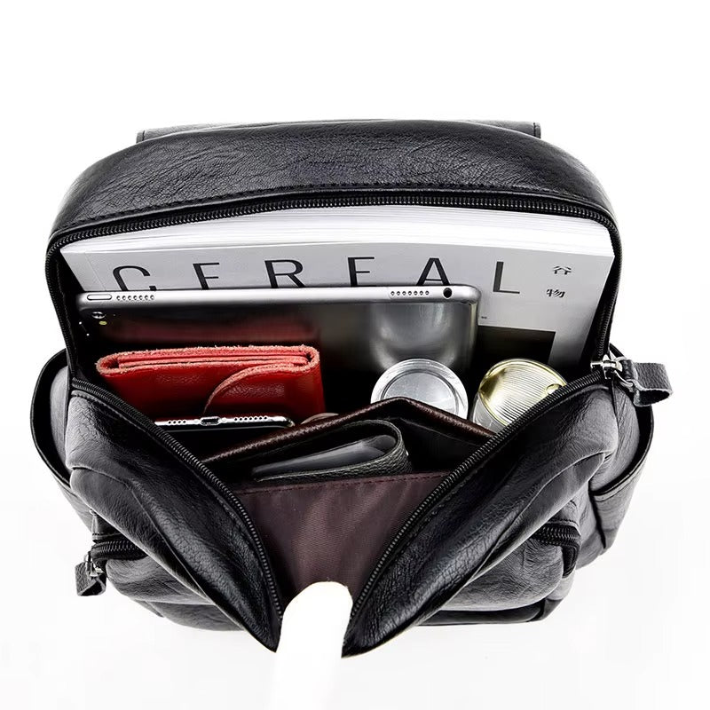 Black leather bag with compartments containing a cereal box, phone, and other items on a white background