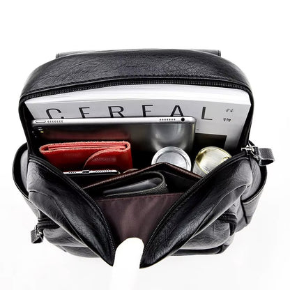 Black leather bag with compartments containing a cereal box, phone, and other items on a white background