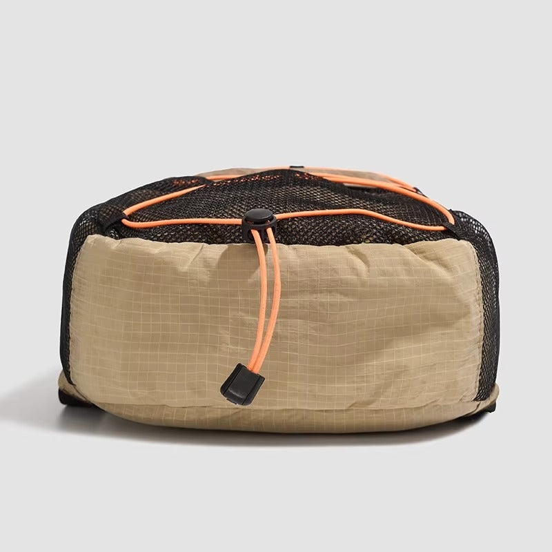 Beige travel pouch with black mesh side and orange zipper on a light gray background