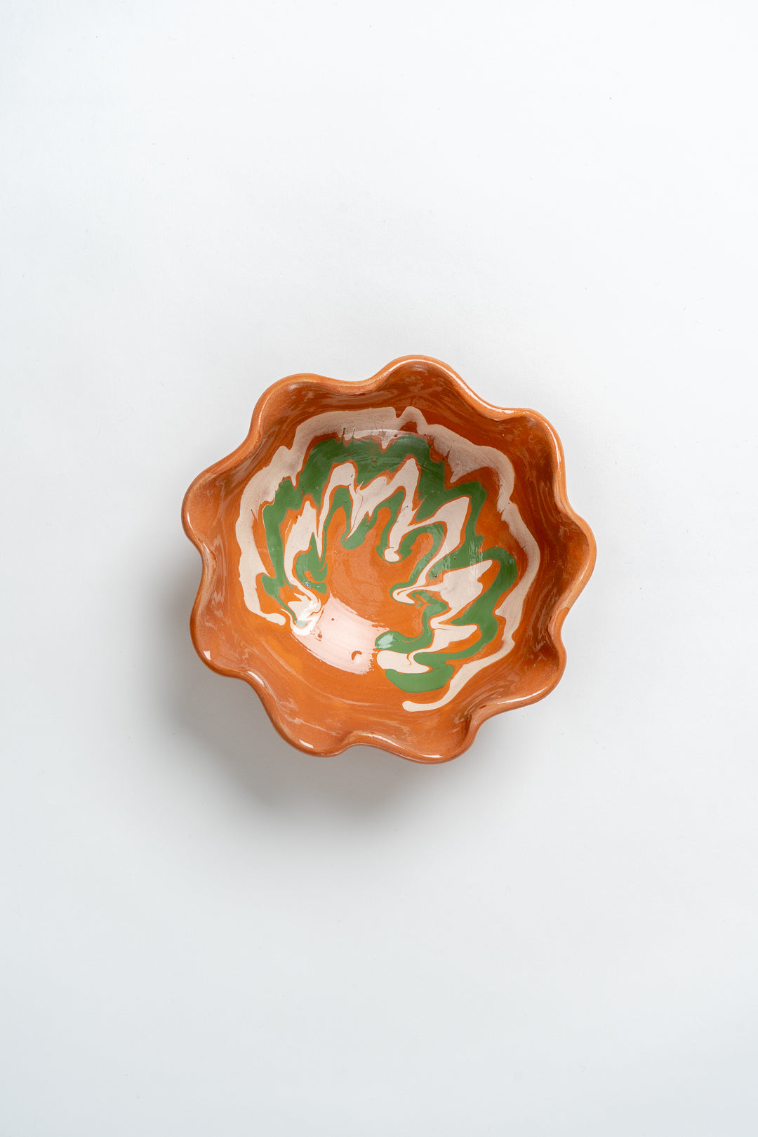 A small ceramic bowl with a marbled design and frill edge, predominantly in a orange colour. Collaboration between MIMMO Studios x Casa De Folklore.